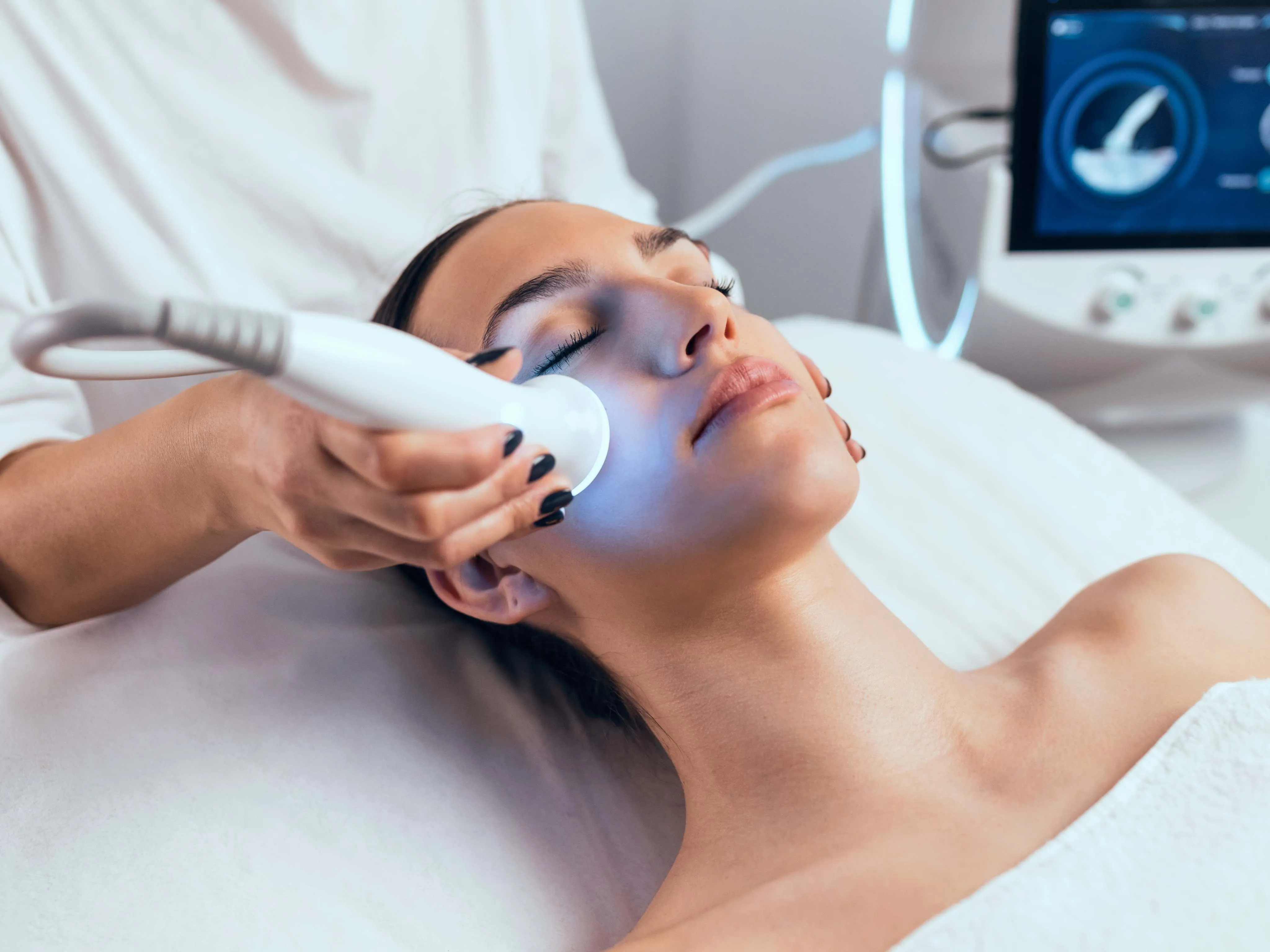 Woman receiving advanced facial treatment with LED therapy for skin rejuvenation at a dermatology clinic.