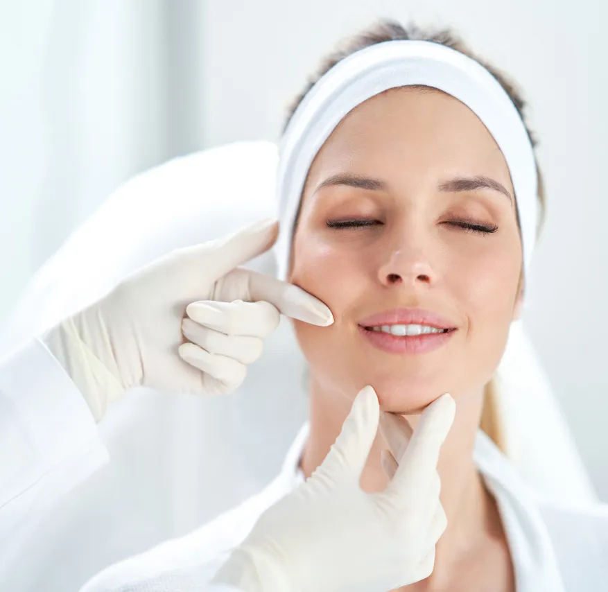  Woman with white headband, eyes closed, receiving professional skincare consultation in clinic