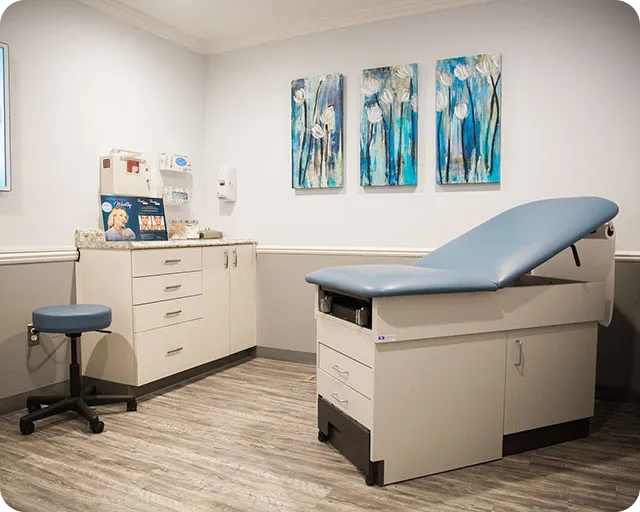 Modern dermatology clinic exam room with medical bed and equipment for skin consultations, treatments, and procedures.