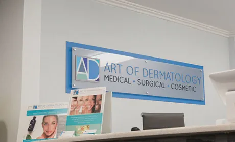Art of Dermatology clinic reception area with signage highlighting medical, surgical, and cosmetic dermatology services.