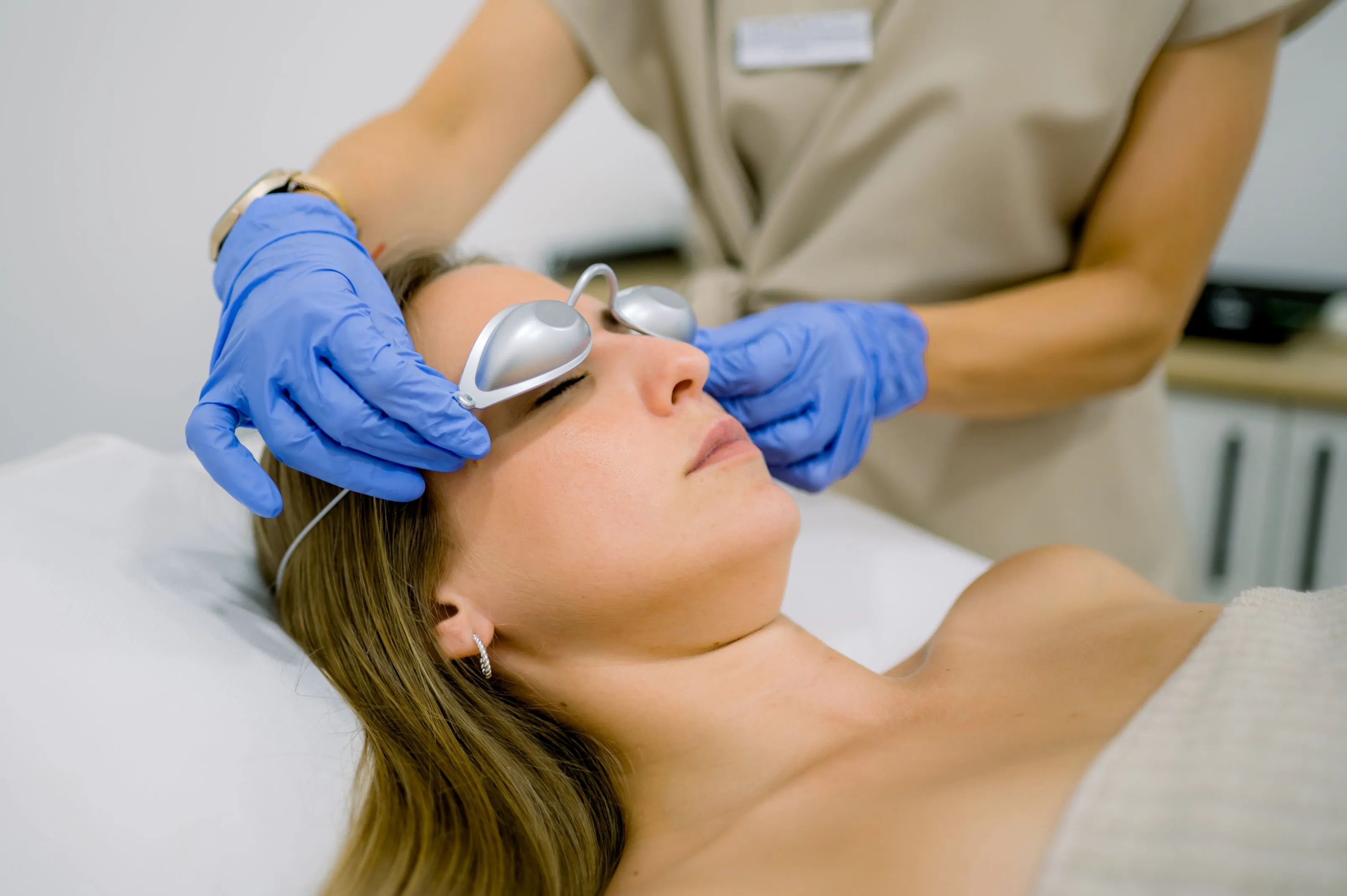 Patient preparing for laser skin treatment at a dermatology clinic, wearing protective eyewear for safe cosmetic procedures.