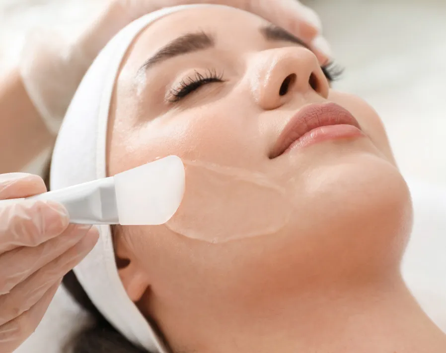 Woman receiving professional TCA Peel facial treatment with handheld device in clinical spa setting