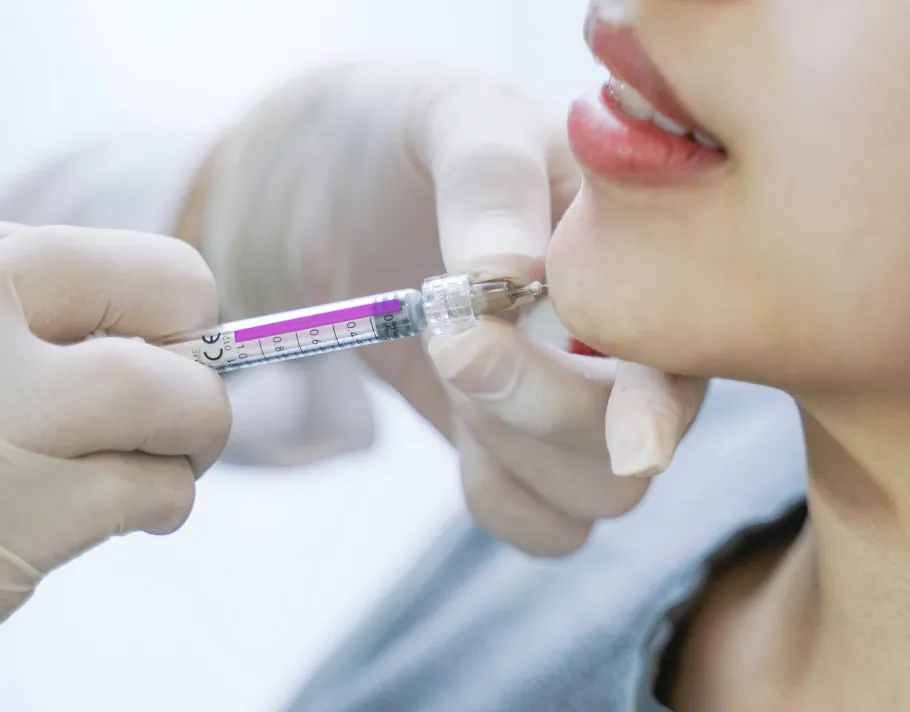 Close-up of person receiving dermal filler injection in chin and jawline by medical professional in clinic