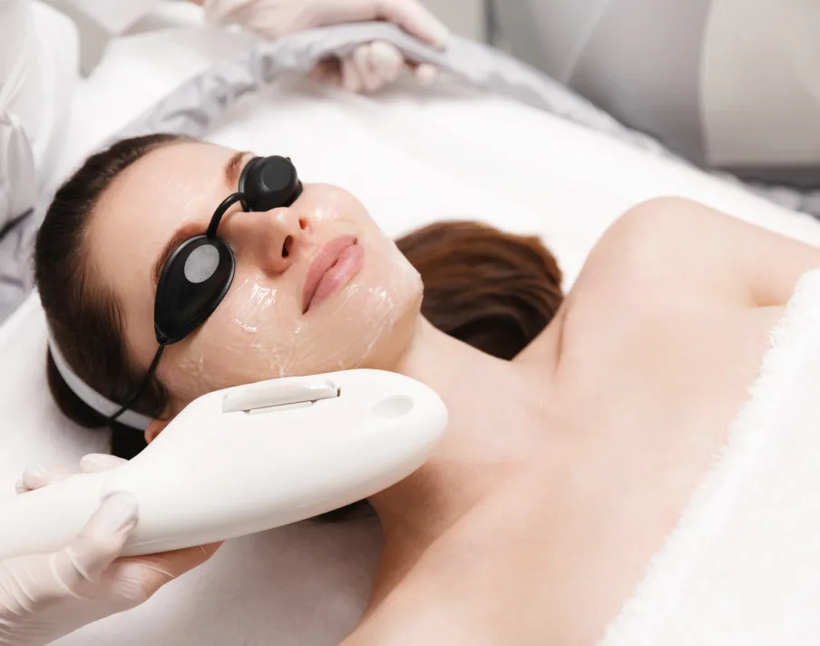 Woman receiving cosmetic treatment on neck and jaw with handheld device