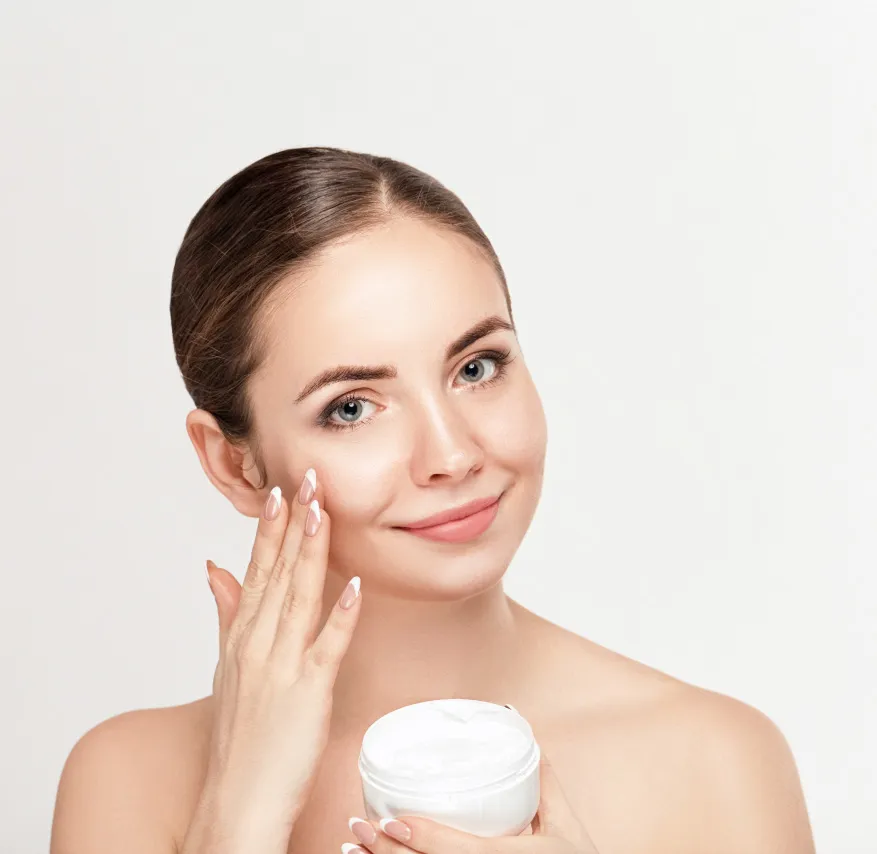 Smiling woman applying dermatologist-recommended moisturizer for healthy, hydrated, and glowing skin care routine.
