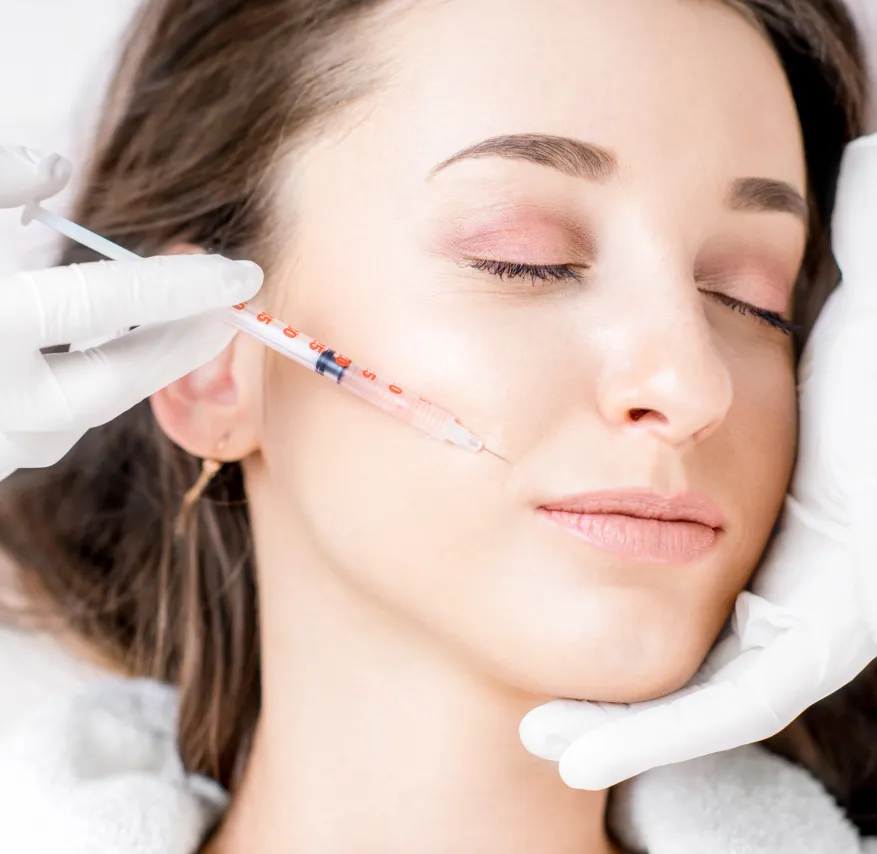 Woman receiving a dermal filler injection in her cheek at a dermatology clinic for facial rejuvenation and volume restoration.